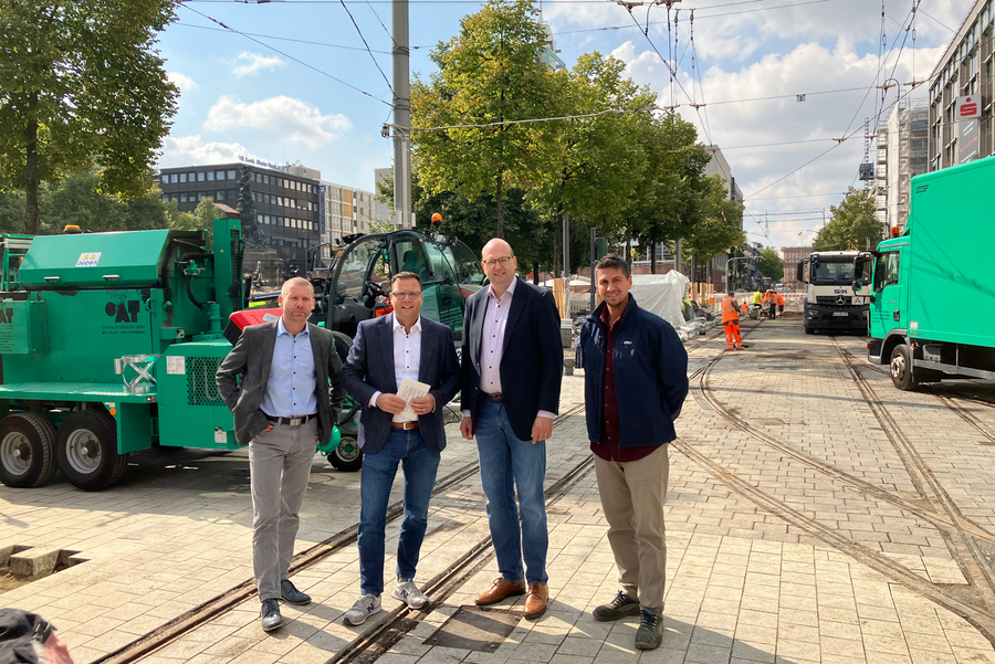 v. l. Frank Dommasch (Bereichsleiter Infrastruktur, rnv), Dr. Volker Proffen (Bürgermeister und ÖPNV-Dezernent der Stadt Mannheim), Marcus Geithe (Geschäftsführer der MV Mannheimer Verkehr GmbH) und Tugay Önal (Projektleiter, rnv) stehen auf den Gleisen in der Baustelle am Paradeplatz mit Blick zum Schloss Mannheim.