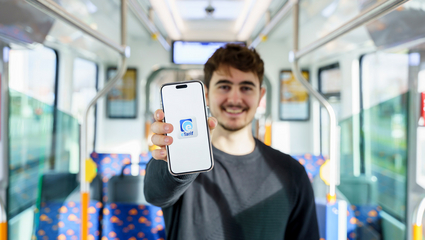 Symbolbild eTarif: Ein Mann steht in einer Straßenbahn der rnv und hält ein Smartphone mit dem Logo der rnv-eTarif-App in die Kamera.