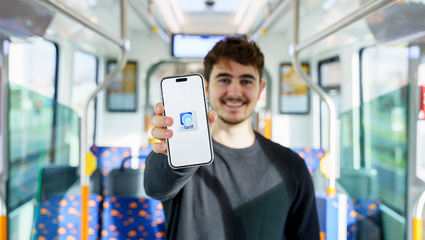 Symbolbild eTarif: Ein Mann steht in einer Straßenbahn der rnv und hält ein Smartphone mit dem Logo der rnv-eTarif-App in die Kamera.